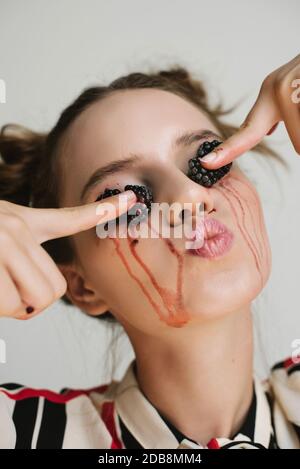 Porträt einer Frau, die Brombeeren auf ihre Augenlider zerquetscht, konzeptuelle Hautpflege Stockfoto