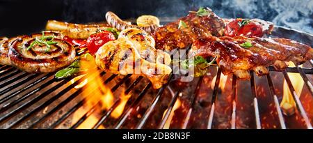 Panorama-Banner mit verschiedenen Fleischgrillen auf einem Grill in einem niedrigen Winkel mit Hühnerbeinen, würzigen Schweinerippen und Würstchen Stockfoto