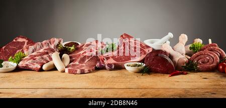 Eine Auswahl an rohem Gourmetfleisch auf einem rustikalen Holzhackbrett mit einem einfachen Hintergrund und Kopierraum. Stockfoto