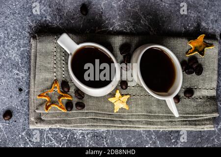 Zwei Tassen Kaffee auf einem gefalteten Geschirrtuch mit Geröstete Kaffeebohnen Stockfoto