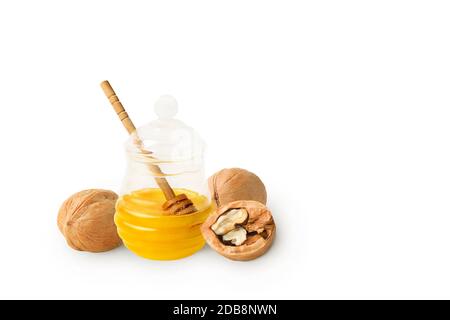 Natürlicher hausgemachter Honig in einem Glasgefäß mit Tropflöffel, mit ganzen und halben Walnüssen. Isoliert auf weißem Hintergrund mit einem Schatten. Stockfoto