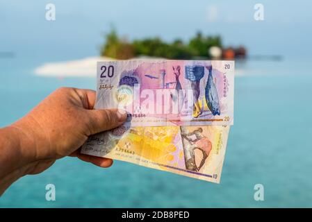 Von einer touristischen zeigen Maledivische rufiyaa Bank Hinweis Wenn Sie reisen in Malediven. Geld der Malediven Bank Note in der Hand der Frauen auf dem Hintergrund der isl Stockfoto