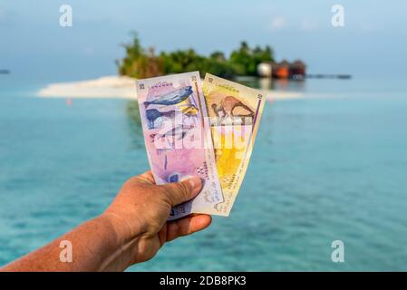 Von einer touristischen zeigen Maledivische rufiyaa Bank Hinweis Wenn Sie reisen in Malediven. Geld der Malediven Bank Note in der Hand der Frauen auf dem Hintergrund der isl Stockfoto