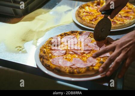 Frisch gebackene Pizza in mehrere Stücke geschnitten. Stockfoto