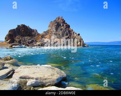 Ein malerischer Felsen vor dem Hintergrund von schmelzendem Eis am See an einem klaren sonnigen Tag. Stockfoto