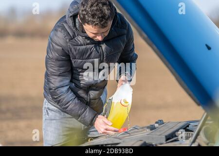 Der Fahrer gibt dem Spezialtank im Fahrzeug gelbe Wischflüssigkeit hinzu. Stockfoto