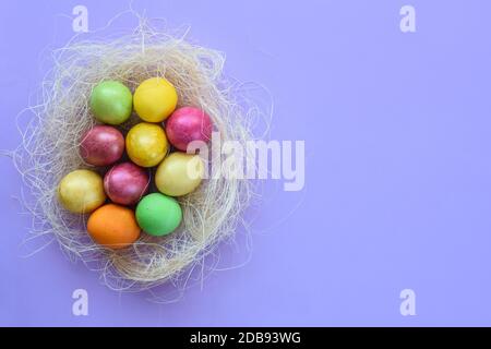 Ostereier in einem provisorischen Nest auf einem lila Hintergrund Stockfoto