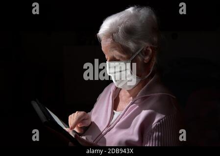 Ältere Frau mit Schutzmaske chattet mit Tablet-Computer Stockfoto