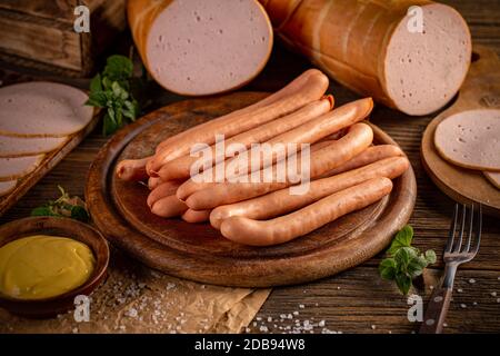 Frische Würstchen mit Senf auf Holzbrett serviert Stockfoto