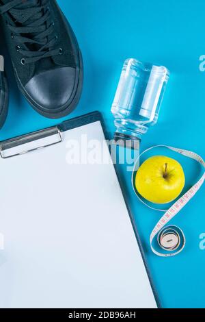Diät-Plan. Weißes Blatt auf der Tablette und Äpfel mit Maßband auf hellblauem Hintergrund. Schlankheits- und Detox-Konzept. Stockfoto