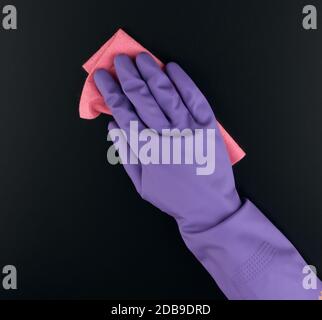 Die Hand hält einen pinken Lappen Schwamm für die Reinigung, schützende lila Gummihandschuh wird auf dem Arm getragen, Nahaufnahme Stockfoto
