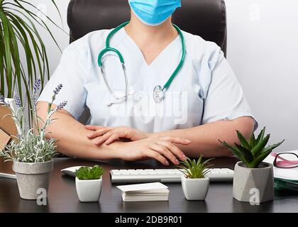 Arzthandschuhe sitzen an einem weißen Arbeitstisch in seinem Büro, Konzept der Patientenaufnahme in der Klinik, Hände vor der Brust verbunden, fokussierte Pose Stockfoto