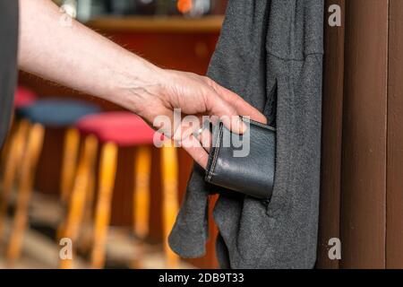 Eine Person stiehlt in einem Pub eine Brieftasche aus einer Jacke Stockfoto