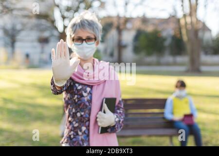 Großmutter gibt Stop-Zeichen zu covid-19 Schutz ihres Enkels und Selbst Stockfoto