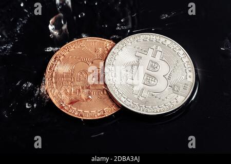 Bitcoin auf schwarzem Hintergrund. Bitcoin waschen mit Wasser. Wirtschaftskrise. Stockfoto