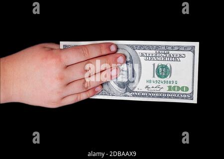 Man's Hand hält eine einhundert US-Dollar teure Rechnung mit einem Porträt des amerikanischen Präsidenten Benjamin Franklinan isolierten schwarzen Hintergrund. Stockfoto