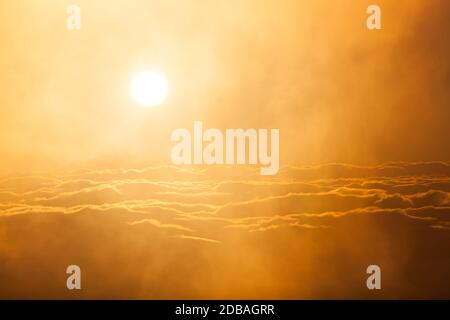 Die Sonne sieht aus wie ein leuchtender orangefarbener Feuerball Als es den Nebel und Nebel über einem erhellt Dicke Wolkenschicht, die das Tal am Sandia bedeckt Moun Stockfoto