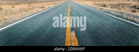 Lange gerade Straße durch Wüste, leere Straße, die in den Horizont führt, zweispurige Asphaltstraße Stockfoto