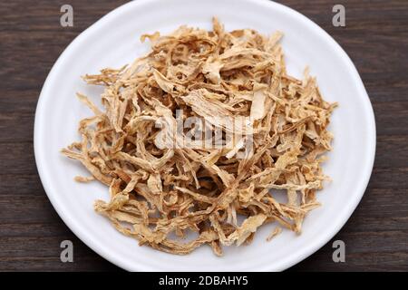 chinesische Medizin, getrocknete Pflanzen auf einem Teller auf einem Holztisch. Stockfoto