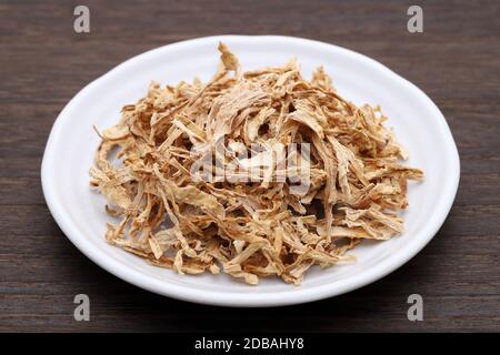 chinesische Medizin, getrocknete Pflanzen auf einem Teller auf einem Holztisch. Stockfoto