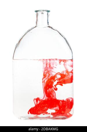 Rotes Aquarell löst sich in Wasser in Glasflasche auf weißem Hintergrund isoliert Stockfoto