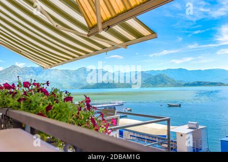 Terrasse des Cafés auf Scadar See in der Nähe Dock mit touristischen Booten Stockfoto