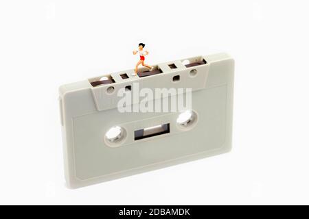 Miniatur Frau läuft auf einer Musikkassette Stockfoto