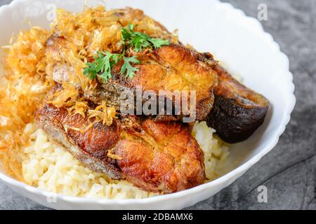 Frittierte scheiben Pangasius Fisch mit Knoblauch, mit braunem Reis serviert. Stockfoto