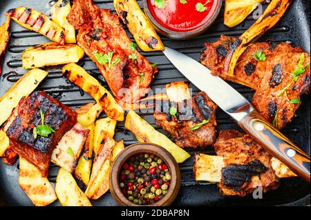 Gegrillte Kalbsrippchen mit Bratkartoffeln in einer Grillpfanne.Grillrippchen und pommes frites Stockfoto