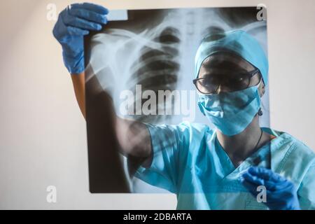 Konzeptuelles Bild eines Arztes, der eine Röntgenaufnahme einiger Lungen hält und analysiert. Stockfoto
