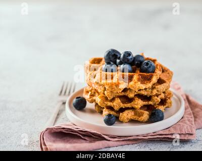 Einfache gesunde glutenfreie Haferwaffeln mit Kopierplatz. Stapel von appetitlichen hausgemachten Waffeln mit Hafermehl dekoriert Heidelbeeren, auf dem Teller über Licht g Stockfoto