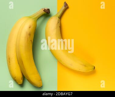 Drei reife Bananen auf grünem und gelbem Hintergrund Stockfoto
