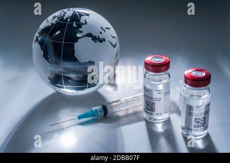 Glaskugel und Spritze mit Impfstoff auf grauem Hintergrund Stockfoto