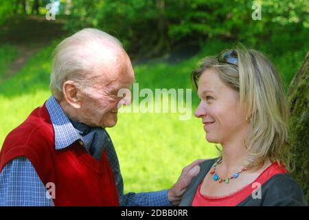 Glücklicher 90-jähriger Mann und junge Frau lächeln in ihre Augen Stockfoto