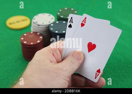 Eine Hand, die ein Paar Asse mit Casino-Chips im Hintergrund Texas Holdem Poker besten Tasche Raketen amerikanischen Fluggesellschaften Stockfoto