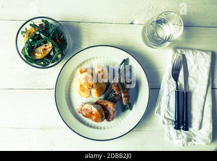 Schweinsmedaillons mit Kartoffeln und Bohnen in Speck gewickelt. Stockfoto