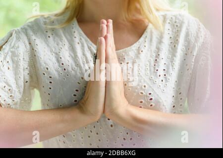 Nahaufnahme einer blonden Frau, die Yoga mit verschlammten Händen macht Stockfoto
