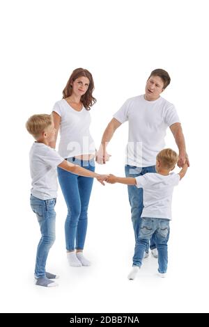 Schwangere Mutter und Vater mit zwei Söhnen auf weißem Hintergrund. Eltern mit Kindern spielen: Hände im Kreis halten und herumlaufen oder tanzen Stockfoto
