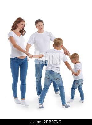 Schwangere Mutter und Vater mit zwei Söhnen auf weißem Hintergrund. Eltern mit Kindern spielen: Hände im Kreis halten und herumlaufen oder tanzen Stockfoto