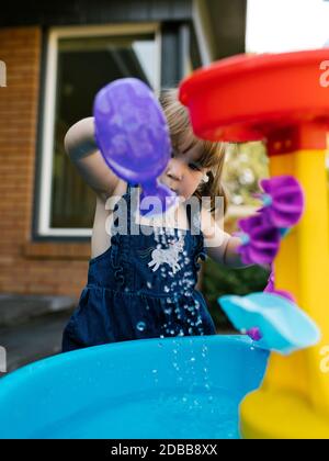 Kleinkind Mädchen (2-3) spielt mit Wasser im Garten Stockfoto