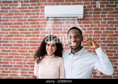 Portrait von glücklichen Paar hält Fernbedienung Klimaanlage Stockfoto