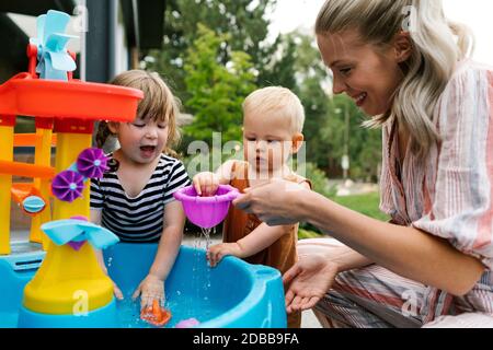 Mutter mit Kleinkind (18-23 Monate) Und Kleinkind Tochter (2-3) spielen mit Wasser im Garten Stockfoto