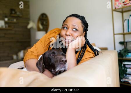 Frau liegt auf dem Sofa mit ihrem Hund Stockfoto