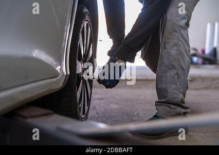 Schrauben Sie das Rad mit einem Drehmomentschlüssel an das Fahrzeug. Austausch von Saisonreifen in einer Autowerkstatt. Stockfoto