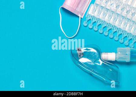 Behandlungskonzept für Coronavirus. Eine medizinische Gesichtsmaske oder Vernebler zur Behandlung der Atemwege weitere Ampullen und eine chirurgische Maske flach gelegt Stockfoto