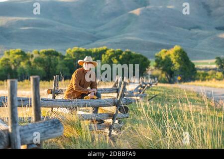 USA, Idaho, Bellevue, Rancher lehnt sich gegen den Zaun auf dem Feld Stockfoto