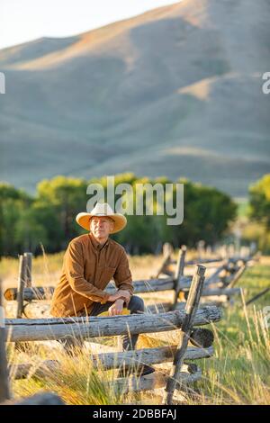 USA, Idaho, Bellevue, Rancher lehnt sich gegen den Zaun auf dem Feld Stockfoto