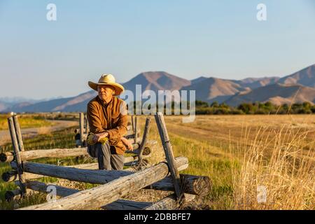 USA, Idaho, Bellevue, Rancher lehnt sich gegen den Zaun auf dem Feld Stockfoto