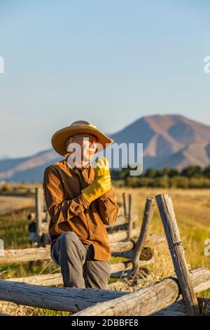 USA, Idaho, Bellevue, Rancher stehen am Zaun und ziehen Handschuhe an Stockfoto