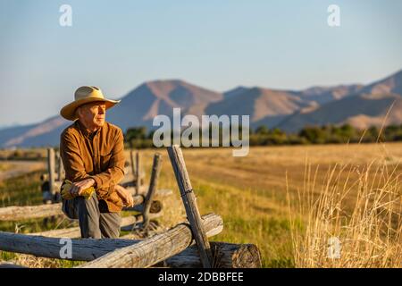 USA, Idaho, Bellevue, Rancher lehnt sich gegen den Zaun auf dem Feld Stockfoto